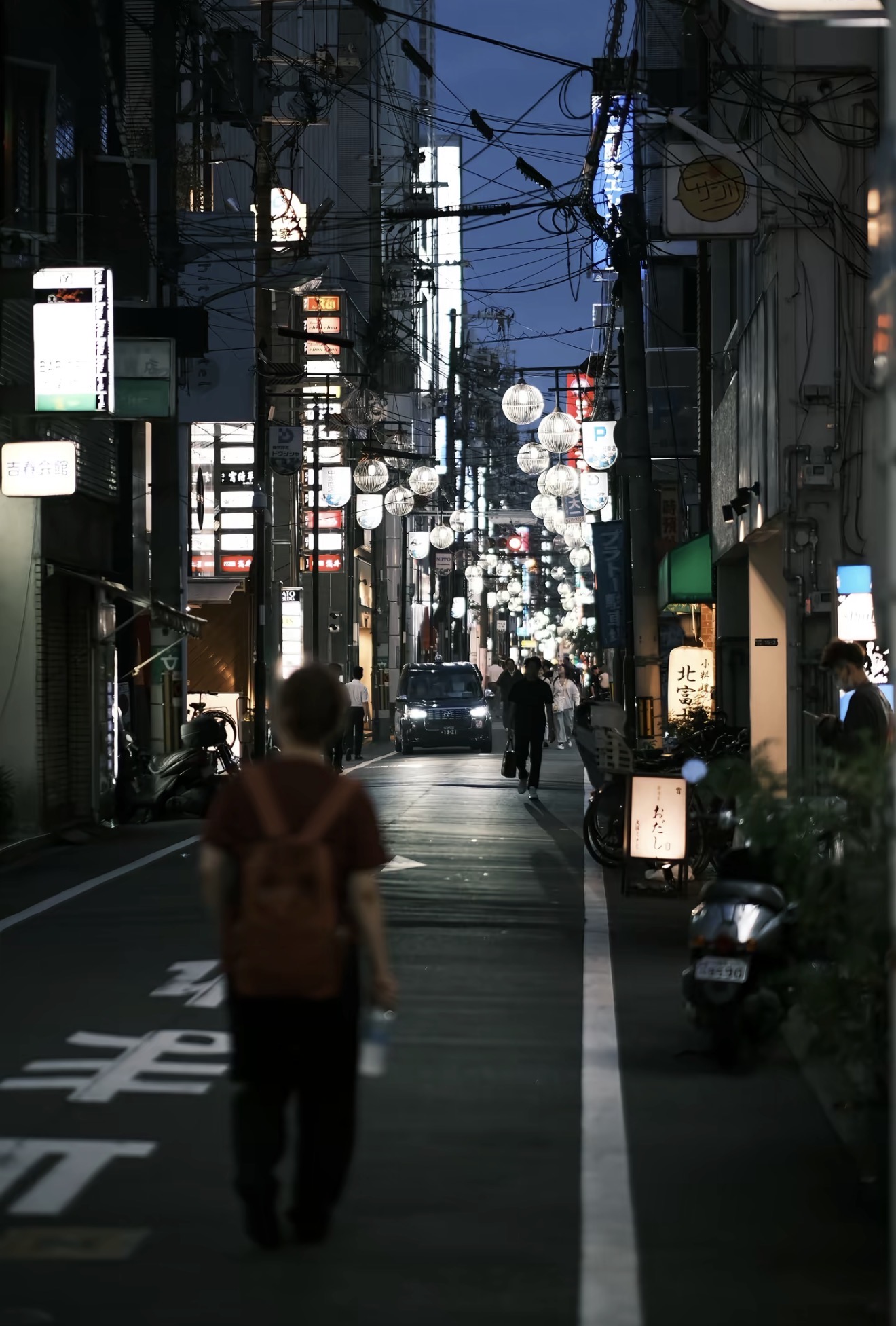 A figure walking through a Tokyo alley at night